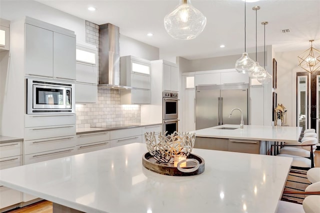 kitchen featuring a breakfast bar area, built in appliances, a spacious island, and decorative light fixtures