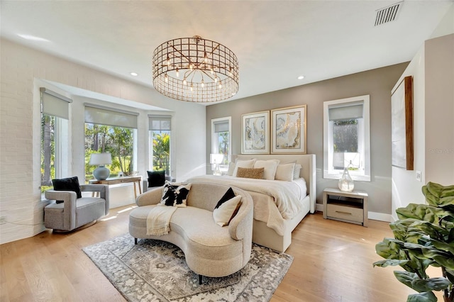 bedroom featuring light hardwood / wood-style floors, multiple windows, and a notable chandelier