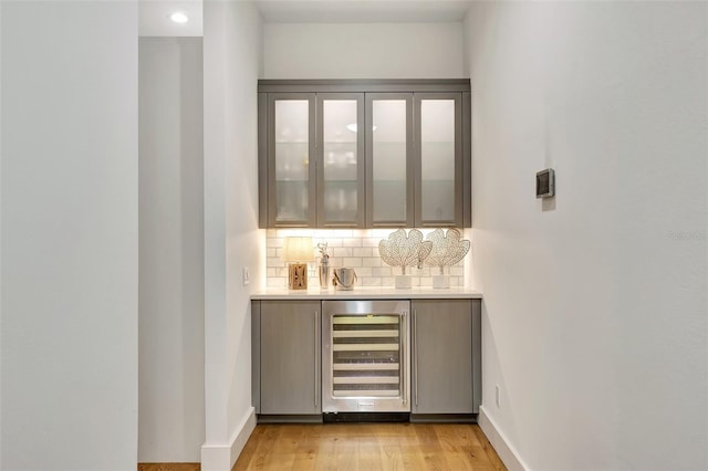 bar featuring backsplash, wine cooler, and light wood-type flooring