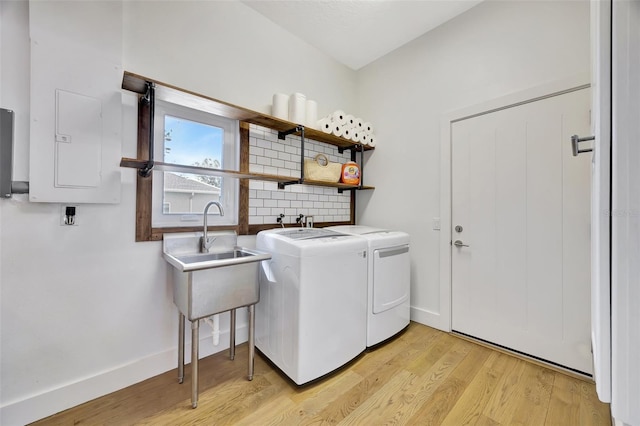 laundry room featuring light hardwood / wood-style floors, sink, electric panel, and washing machine and clothes dryer