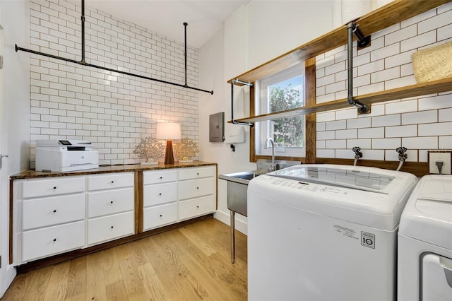 laundry area with independent washer and dryer, light hardwood / wood-style floors, and sink