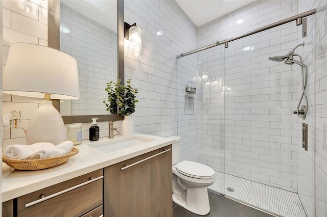 bathroom with vanity, toilet, tile walls, and a shower with shower door