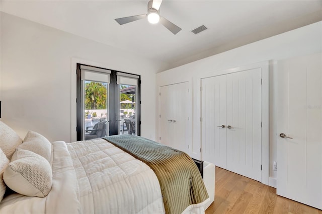 bedroom featuring access to exterior, ceiling fan, french doors, light hardwood / wood-style flooring, and two closets