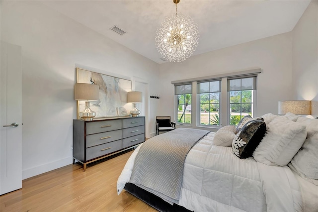 bedroom with light wood-type flooring and an inviting chandelier