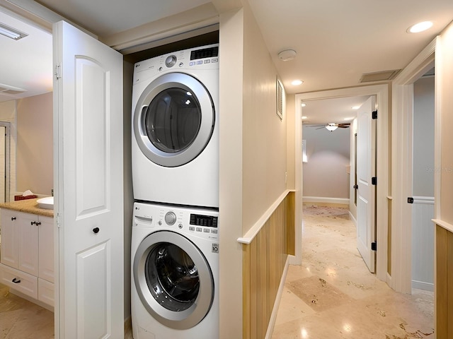 washroom with ceiling fan and stacked washer / dryer