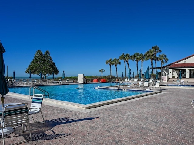 view of pool with a patio and a water view