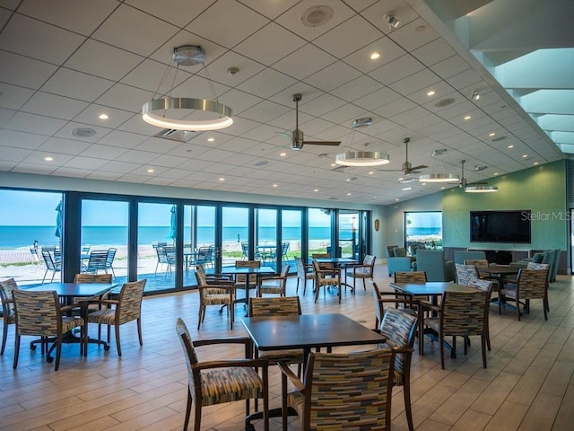 dining area with a water view, light hardwood / wood-style flooring, and ceiling fan