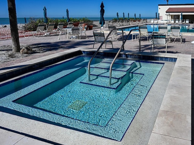 view of swimming pool featuring a patio area and a water view