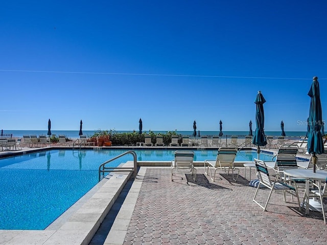 view of pool featuring a water view and a patio