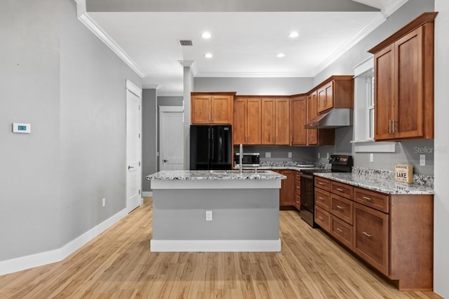 kitchen featuring black appliances, a center island with sink, light stone countertops, and light hardwood / wood-style flooring