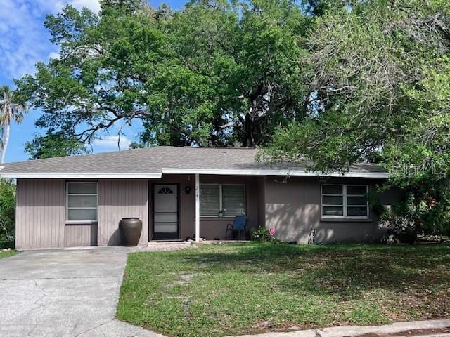 ranch-style home with a front yard and roof with shingles
