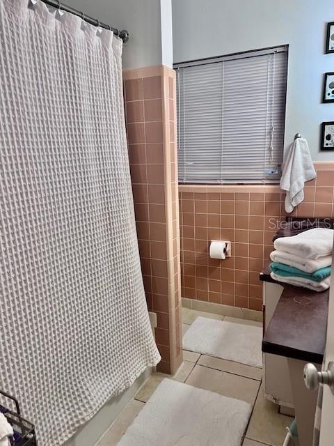 bathroom with tile patterned floors, tile walls, and walk in shower