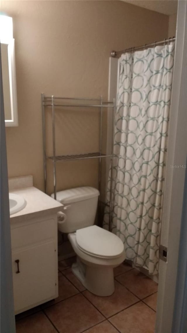 bathroom with tile patterned floors, a shower with curtain, vanity, and toilet