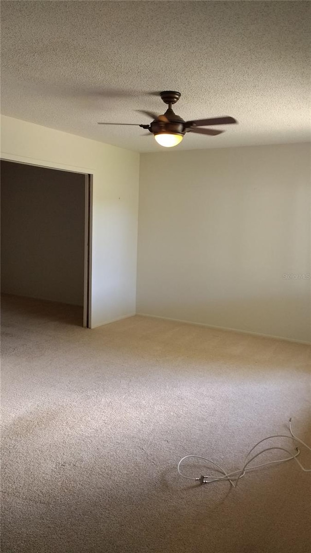 unfurnished room featuring carpet flooring, ceiling fan, and a textured ceiling