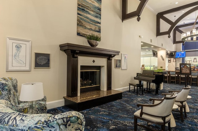 living room with a fireplace, a towering ceiling, and baseboards