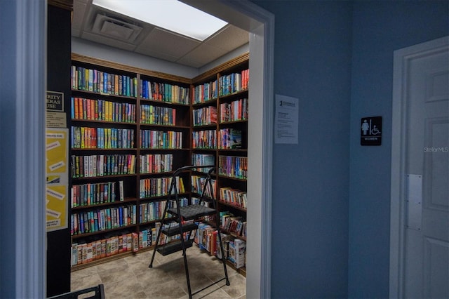 interior space featuring wall of books and a paneled ceiling