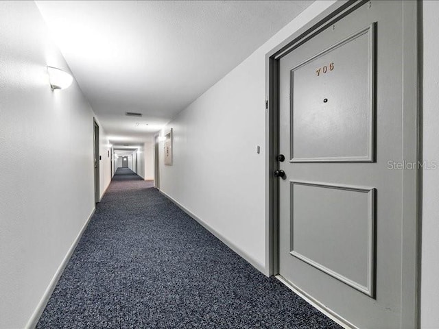 hallway featuring dark carpet