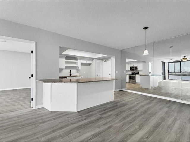 kitchen with pendant lighting, dark hardwood / wood-style flooring, white cabinetry, and stainless steel appliances