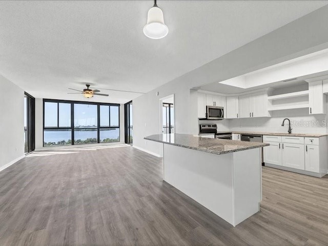 kitchen with hardwood / wood-style floors, pendant lighting, white cabinets, and stainless steel appliances