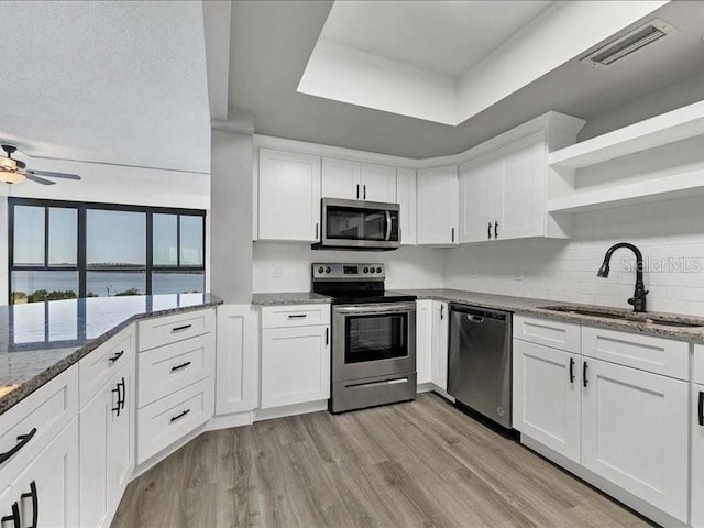 kitchen with appliances with stainless steel finishes, stone countertops, white cabinetry, and sink