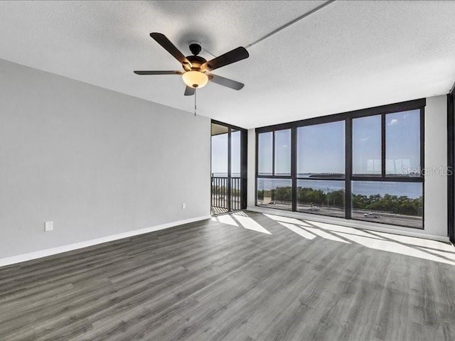 empty room with wood-type flooring, a textured ceiling, a water view, and a healthy amount of sunlight