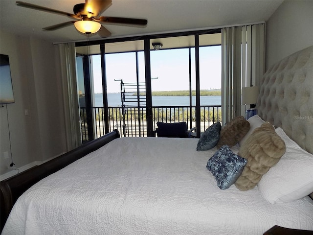 bedroom featuring multiple windows, a wall of windows, a water view, and access to exterior