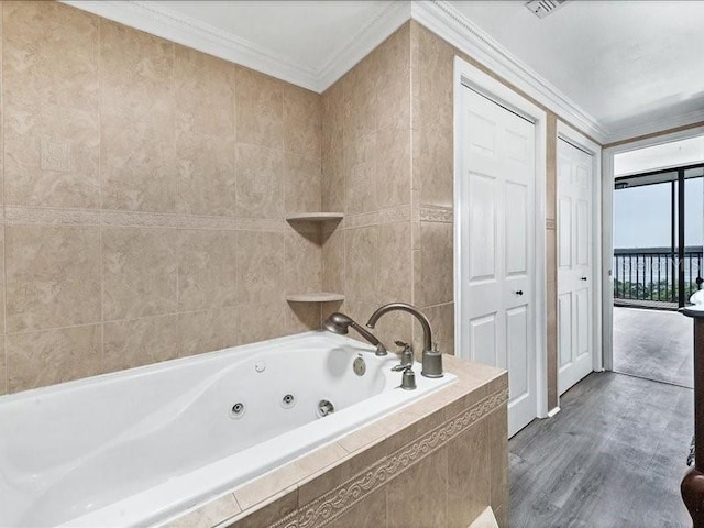 bathroom with a relaxing tiled tub, crown molding, and tile walls