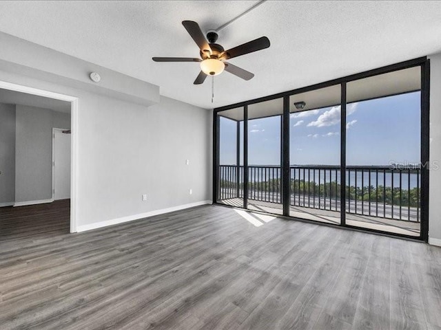 spare room featuring ceiling fan, a water view, a textured ceiling, and hardwood / wood-style flooring