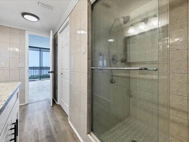 bathroom with hardwood / wood-style floors, an enclosed shower, vanity, tile walls, and ornamental molding