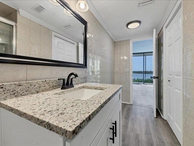 bathroom with vanity, hardwood / wood-style flooring, tile walls, and crown molding