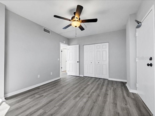 unfurnished bedroom featuring hardwood / wood-style floors, ceiling fan, a textured ceiling, and a closet