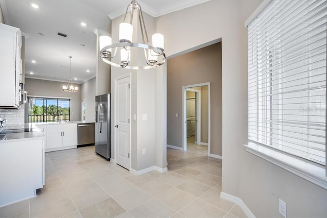 kitchen featuring an inviting chandelier, white cabinets, hanging light fixtures, decorative backsplash, and appliances with stainless steel finishes