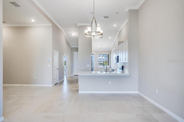 kitchen featuring a chandelier, kitchen peninsula, crown molding, and hanging light fixtures