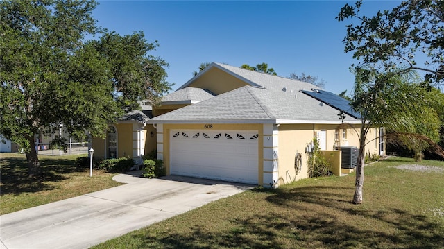 view of front of house featuring solar panels, central air condition unit, a front yard, and a garage