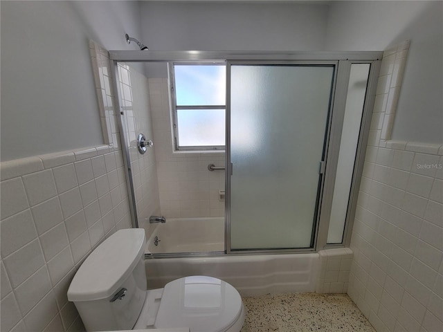 bathroom featuring toilet, tile walls, and enclosed tub / shower combo