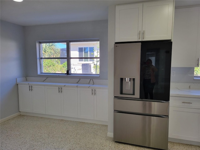 kitchen featuring stainless steel refrigerator with ice dispenser, light stone counters, and white cabinets