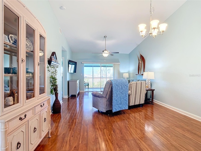 living room with ceiling fan with notable chandelier, dark hardwood / wood-style flooring, and vaulted ceiling