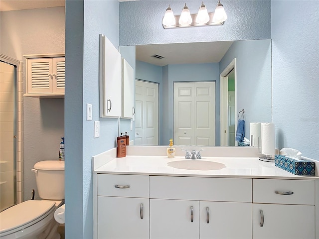 bathroom with vanity, toilet, and a shower with door