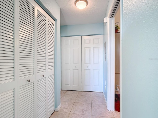 hall featuring light tile patterned floors and a textured ceiling