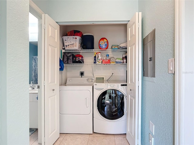 washroom featuring washer and clothes dryer, light tile patterned floors, sink, and electric panel