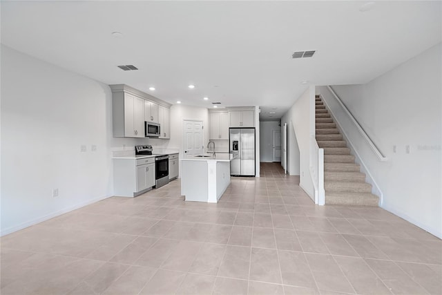 kitchen featuring light tile patterned flooring, appliances with stainless steel finishes, a center island with sink, and sink