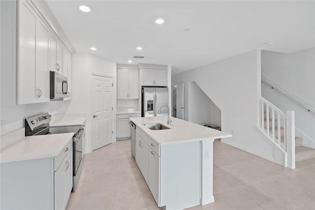 kitchen featuring stainless steel appliances, a kitchen island with sink, sink, light tile patterned floors, and white cabinetry