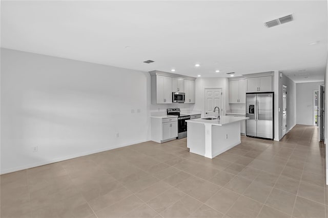 kitchen featuring a center island with sink, light tile patterned flooring, sink, and stainless steel appliances