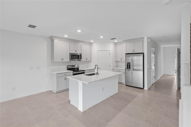 kitchen featuring white cabinetry, sink, a center island with sink, light tile patterned flooring, and appliances with stainless steel finishes