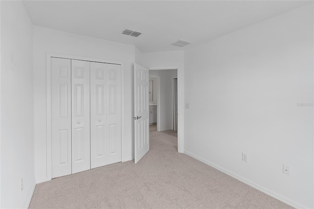 unfurnished bedroom featuring a closet and light colored carpet