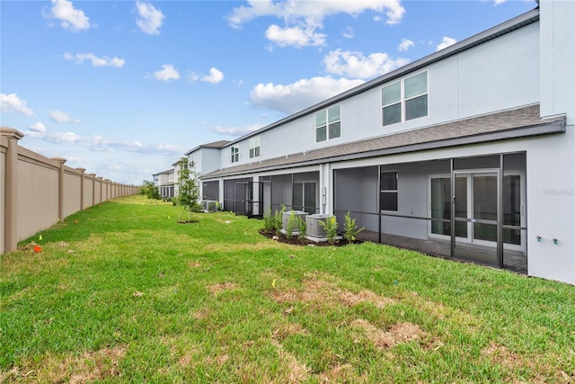 rear view of property featuring a lawn and cooling unit