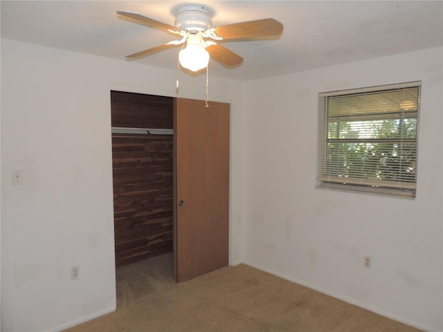 unfurnished bedroom with ceiling fan, wood walls, carpet floors, and a closet