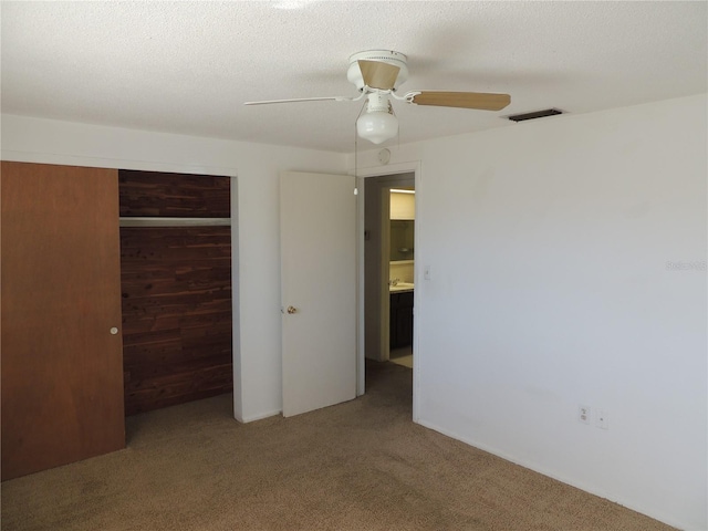 unfurnished bedroom with carpet flooring, ceiling fan, a textured ceiling, and a closet