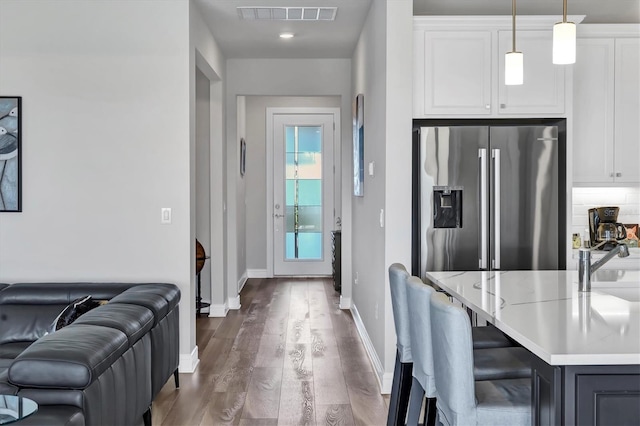 kitchen featuring white cabinets, hanging light fixtures, stainless steel fridge, and a kitchen breakfast bar