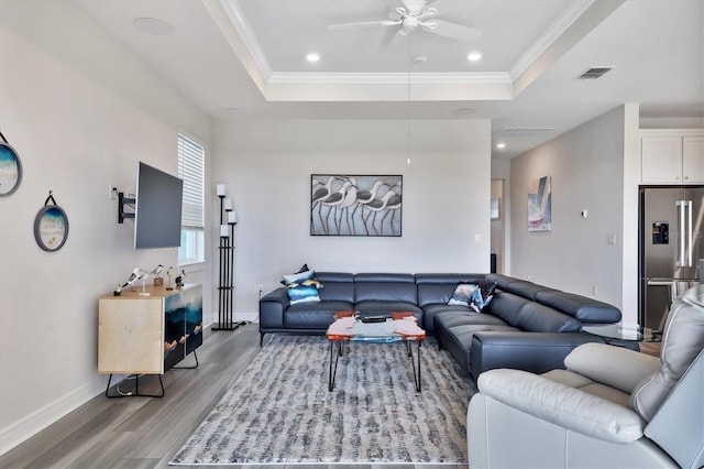 living room featuring wood-type flooring, crown molding, and a tray ceiling